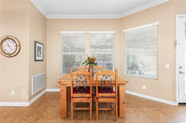 tiled dining room with baseboards, visible vents, and crown molding