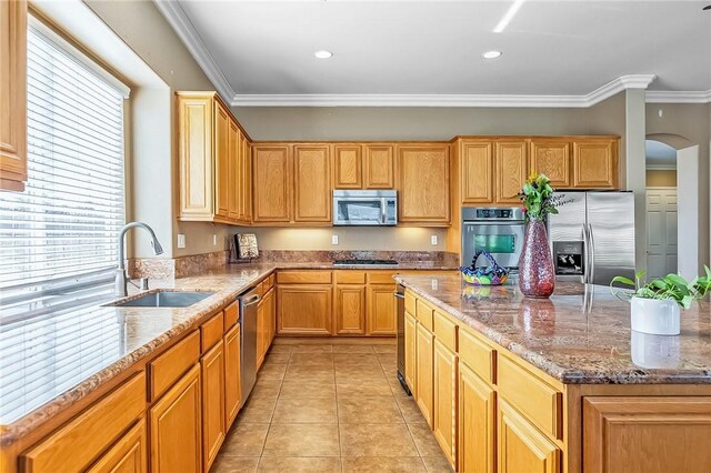 kitchen with light tile patterned flooring, sink, ornamental molding, light stone counters, and stainless steel appliances