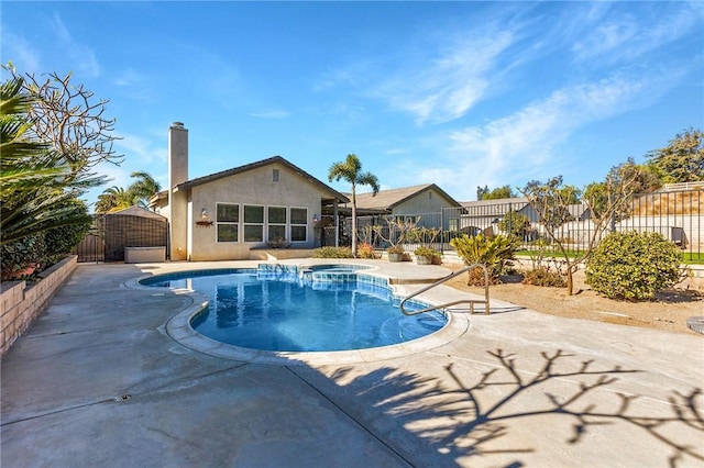 view of swimming pool with a pool with connected hot tub, fence, and a patio