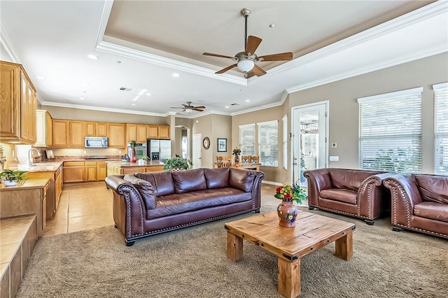 living room featuring light tile patterned flooring, sink, ceiling fan, a raised ceiling, and crown molding