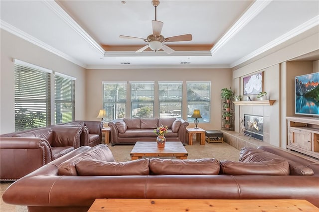 living room with ornamental molding, a tray ceiling, light carpet, and a tile fireplace