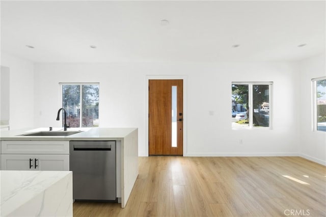 kitchen with white cabinetry, sink, stainless steel dishwasher, and light wood-type flooring