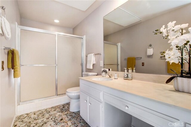 bathroom featuring vanity, toilet, and a shower with shower door