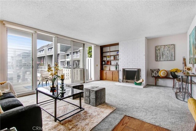 carpeted living room featuring a brick fireplace and a textured ceiling