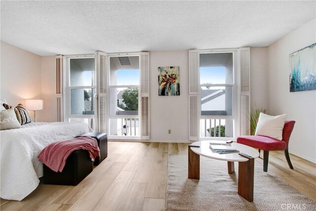 bedroom featuring floor to ceiling windows, a textured ceiling, and light wood-type flooring