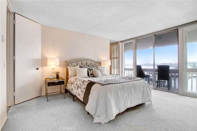 carpeted bedroom featuring a wall of windows, a textured ceiling, and access to outside