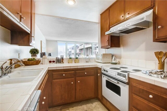 kitchen featuring sink, white appliances, tile countertops, and light tile patterned floors