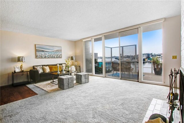 living room featuring floor to ceiling windows, a water view, carpet flooring, and a textured ceiling