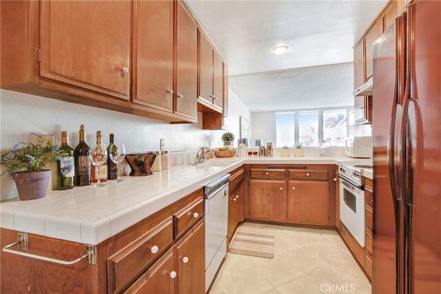 kitchen featuring appliances with stainless steel finishes, tile counters, kitchen peninsula, and sink