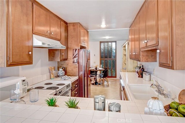 kitchen featuring sink, tile countertops, white appliances, and kitchen peninsula