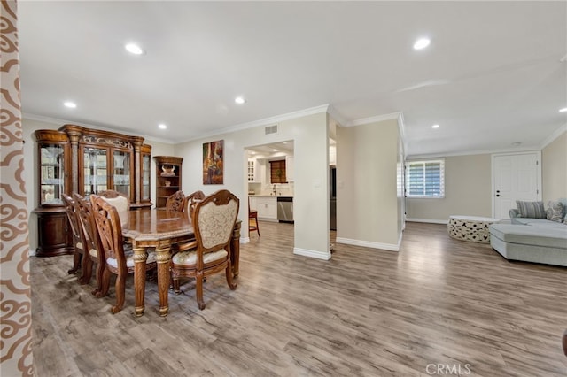 dining area with ornamental molding and light hardwood / wood-style flooring