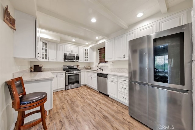 kitchen with beamed ceiling, stainless steel appliances, and white cabinets