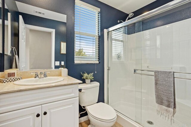 bathroom with walk in shower, vanity, and toilet