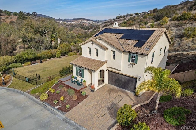 view of front of home featuring a garage, a mountain view, a front yard, and solar panels