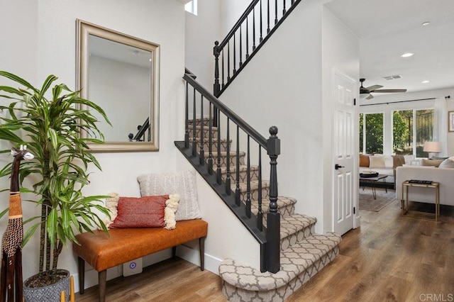 stairway featuring wood-type flooring and ceiling fan