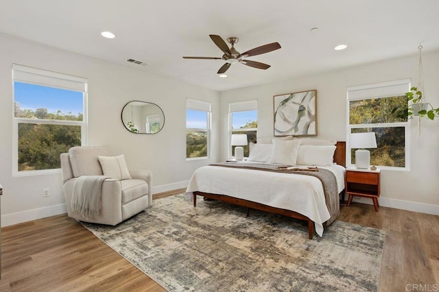 bedroom featuring multiple windows, hardwood / wood-style flooring, and ceiling fan