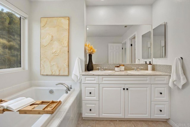 bathroom featuring tiled tub, vanity, tile patterned flooring, and backsplash