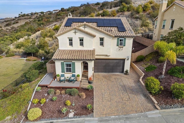 mediterranean / spanish house with a garage, a wooden deck, and solar panels