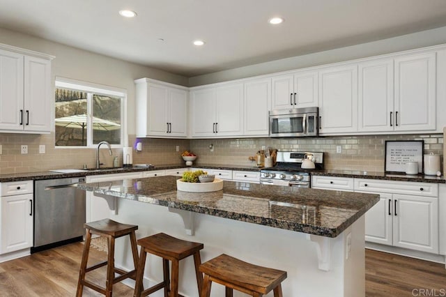 kitchen featuring white cabinetry, appliances with stainless steel finishes, dark hardwood / wood-style flooring, and a kitchen island