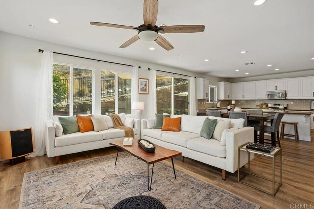 living room featuring ceiling fan and dark hardwood / wood-style flooring