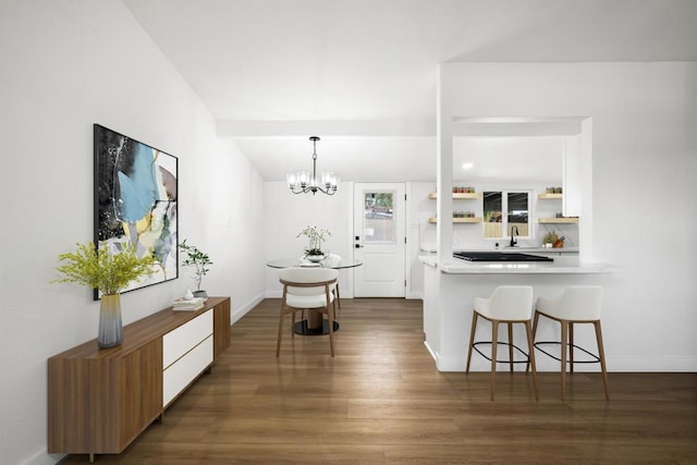 kitchen featuring sink, white cabinets, a kitchen breakfast bar, dark hardwood / wood-style flooring, and an inviting chandelier