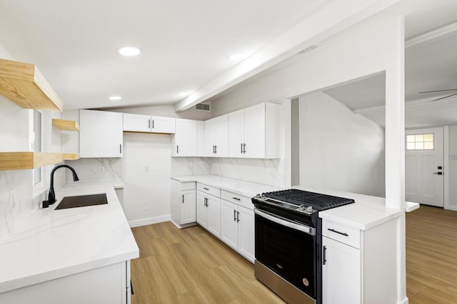 kitchen featuring lofted ceiling with beams, sink, white cabinets, stainless steel gas range, and light hardwood / wood-style flooring