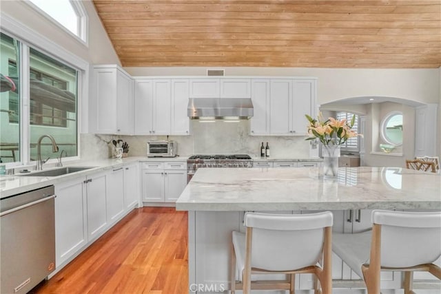 kitchen featuring a breakfast bar area, dishwasher, range, light stone counters, and white cabinets