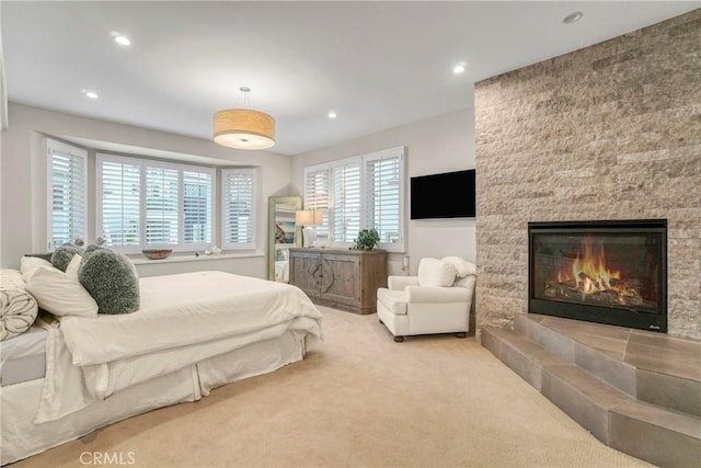 bedroom featuring a large fireplace and light carpet