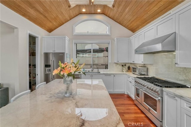 kitchen featuring high end appliances, wood ceiling, light stone counters, and white cabinetry