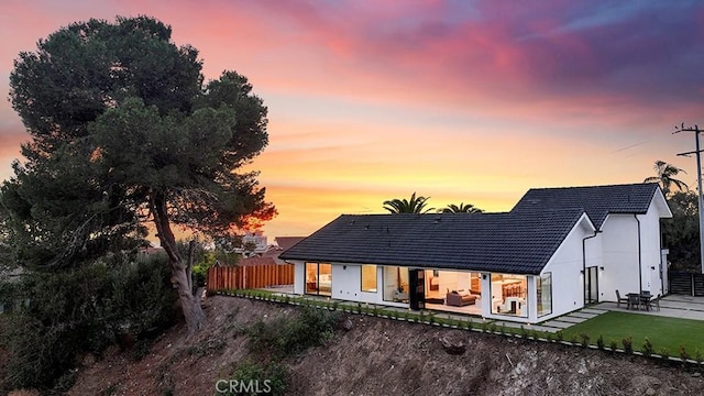 back house at dusk with a yard and a patio