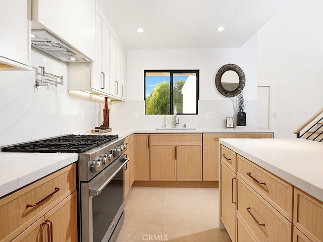 kitchen featuring high end stove, tasteful backsplash, white cabinetry, sink, and light brown cabinets