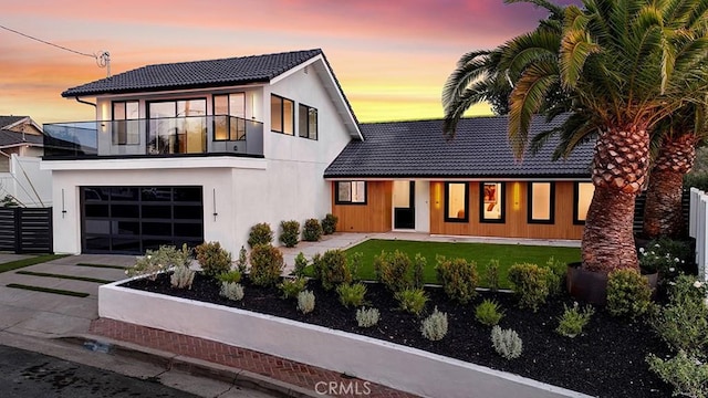 view of front of house featuring a garage, a lawn, and a balcony