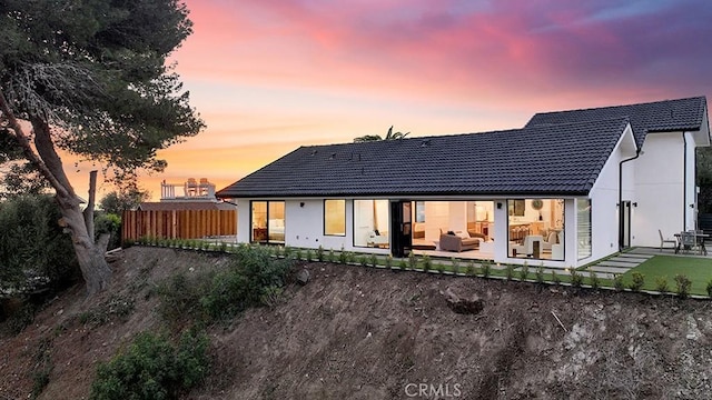 back house at dusk featuring a patio