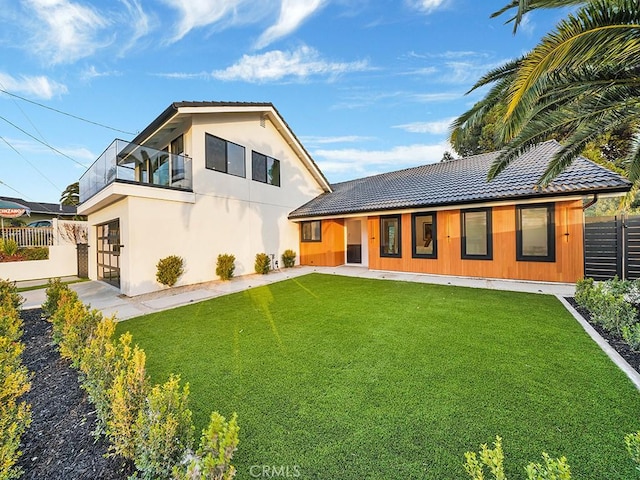 back of house featuring a balcony and a yard