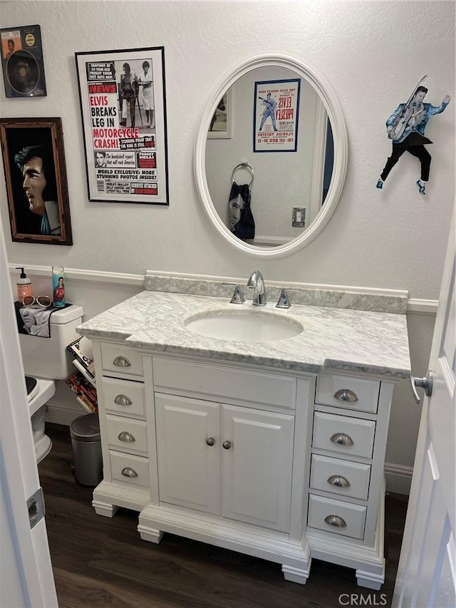 bathroom with toilet, hardwood / wood-style flooring, and vanity