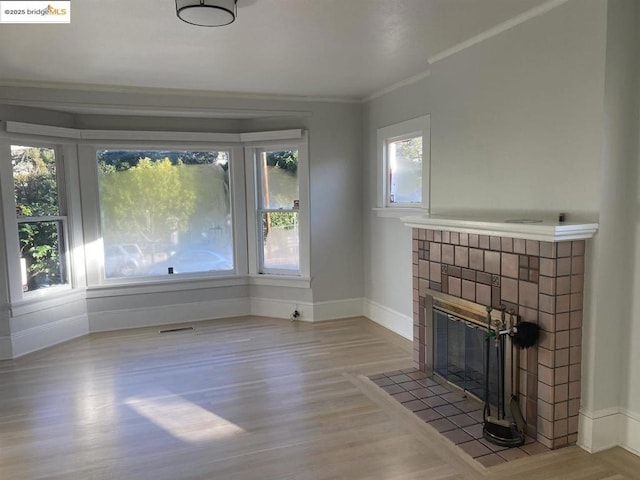 unfurnished living room with crown molding, a fireplace, and light hardwood / wood-style flooring