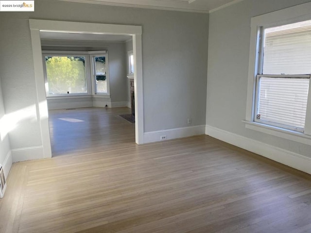 unfurnished room with crown molding and light hardwood / wood-style floors