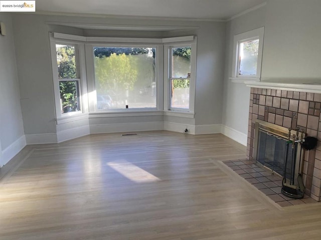 unfurnished living room featuring a fireplace, ornamental molding, and light wood-type flooring