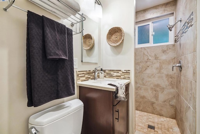 bathroom featuring tasteful backsplash, vanity, toilet, and a tile shower