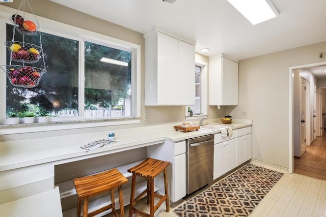 kitchen with sink, stainless steel dishwasher, white cabinets, and a kitchen breakfast bar