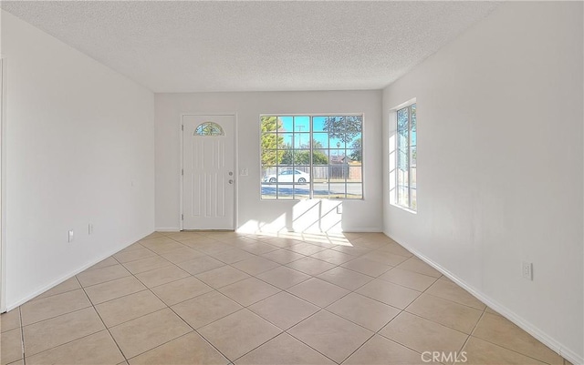 spare room with light tile patterned floors and a textured ceiling