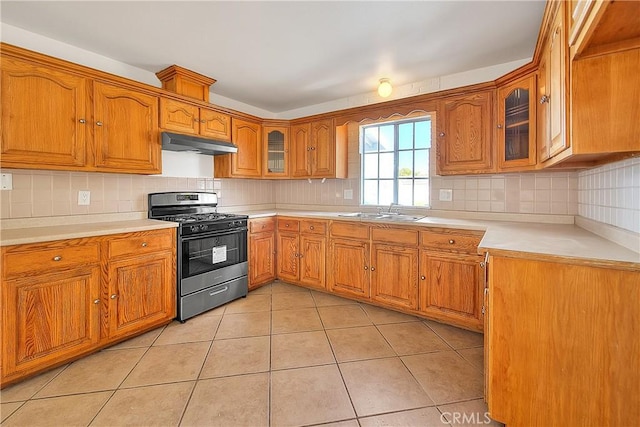 kitchen featuring stainless steel gas stove, sink, light tile patterned floors, and tasteful backsplash