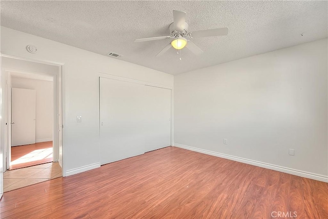 empty room featuring ceiling fan, a textured ceiling, and light hardwood / wood-style flooring