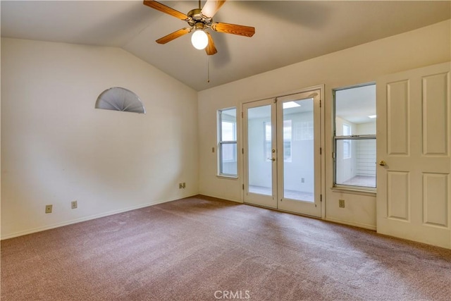 carpeted spare room featuring vaulted ceiling, ceiling fan, and french doors