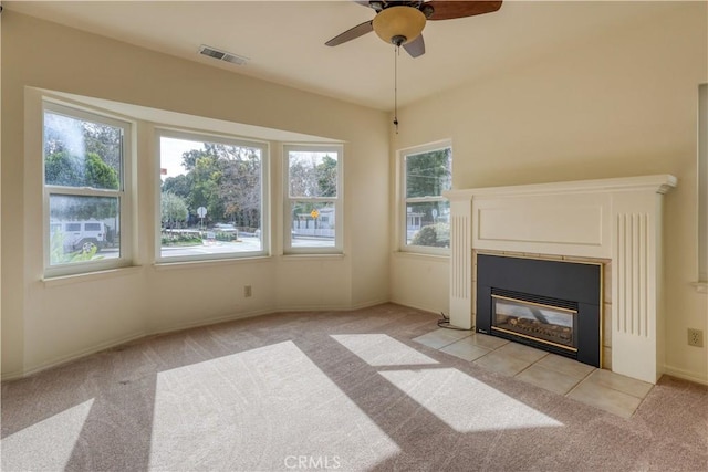 unfurnished living room with ceiling fan, light colored carpet, and a tile fireplace