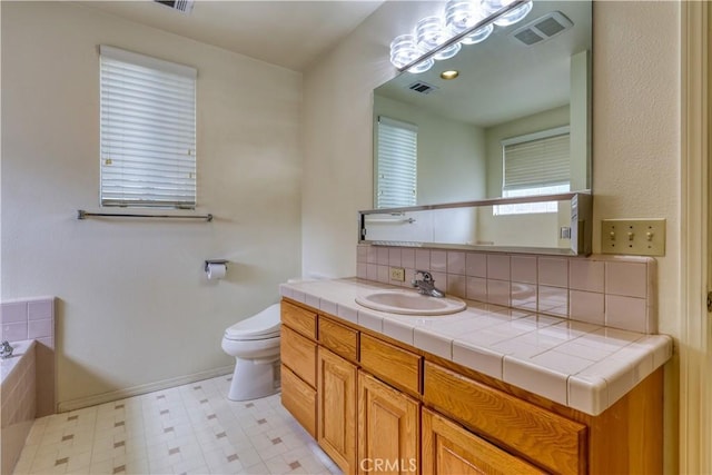 bathroom featuring vanity, backsplash, a tub, and toilet