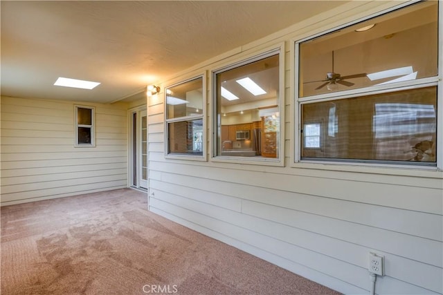 unfurnished sunroom featuring a patio and ceiling fan