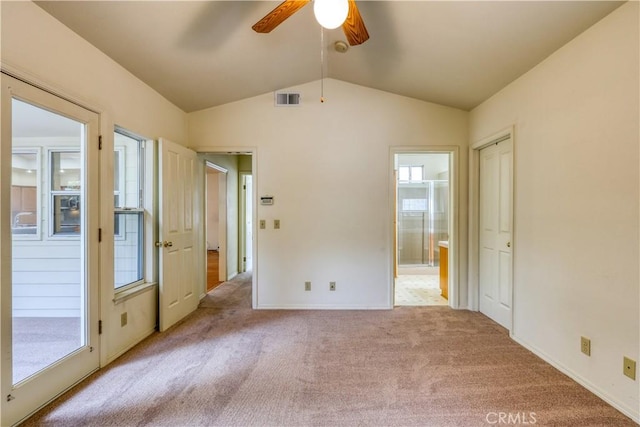 unfurnished bedroom featuring lofted ceiling, light colored carpet, ceiling fan, and ensuite bathroom