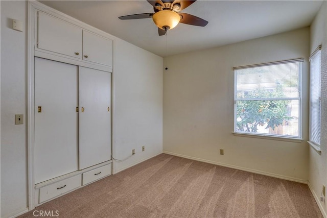 unfurnished bedroom with light colored carpet, a closet, and ceiling fan