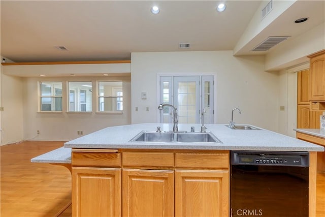 kitchen featuring black dishwasher, sink, a kitchen island with sink, and light hardwood / wood-style floors